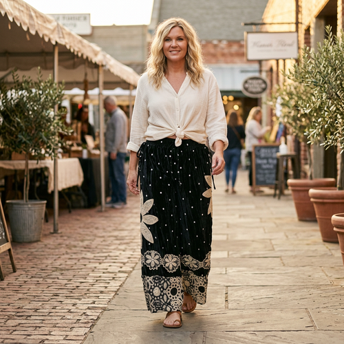 Model walking a market street in black velvet polka dot wide-leg pantaloons with crochet daisy appliqué and lace hems