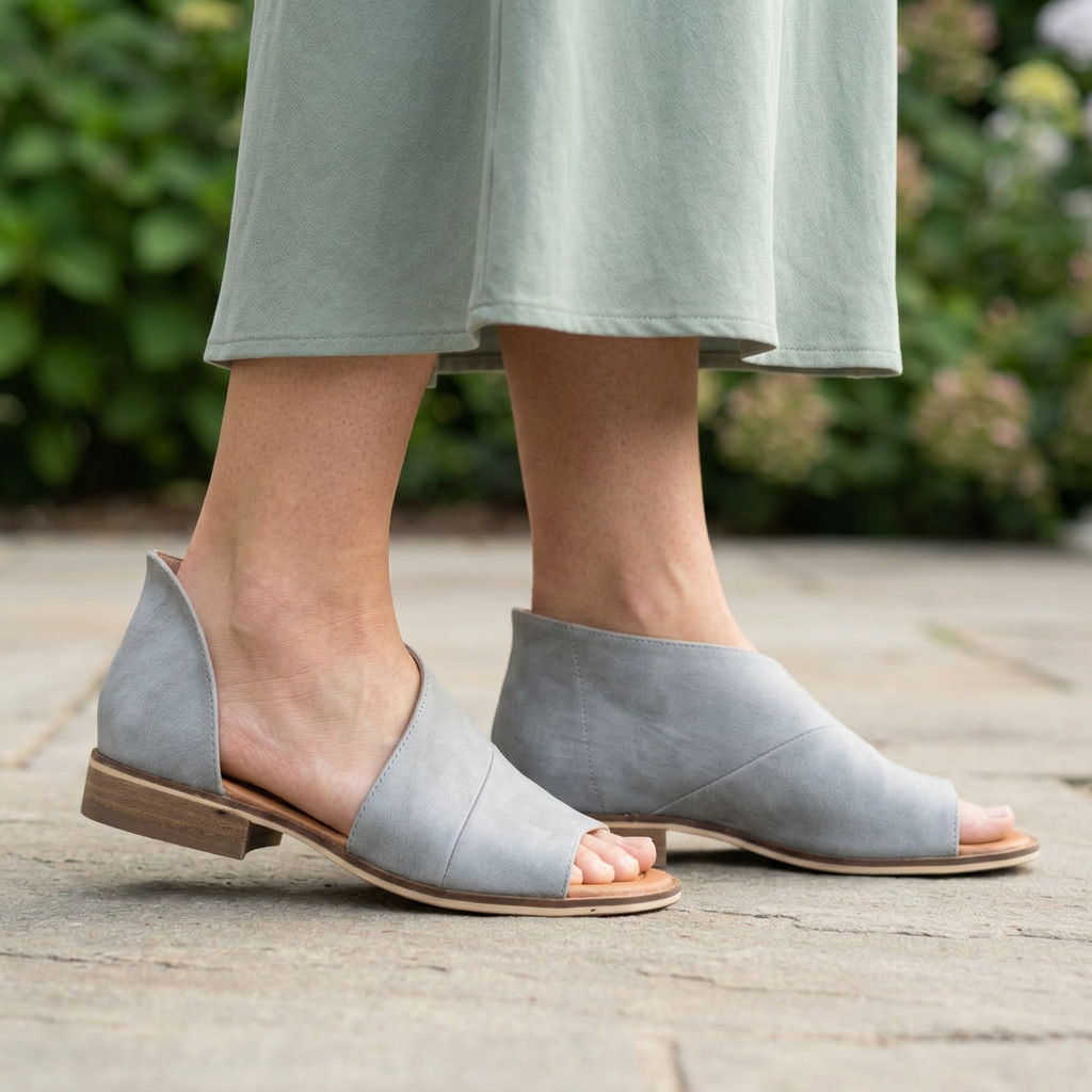 Women's gray open-toe cutout sandals with low wood-look heels worn under a sage dress on a patio