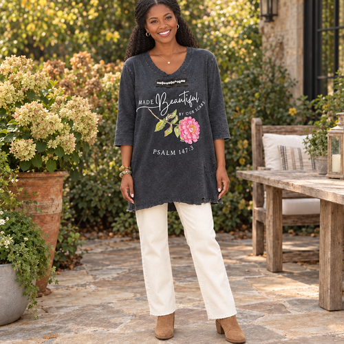 A Rare Bird Shop women's charcoal floral graphic tee with cream jeans on a garden patio - BellanBlue