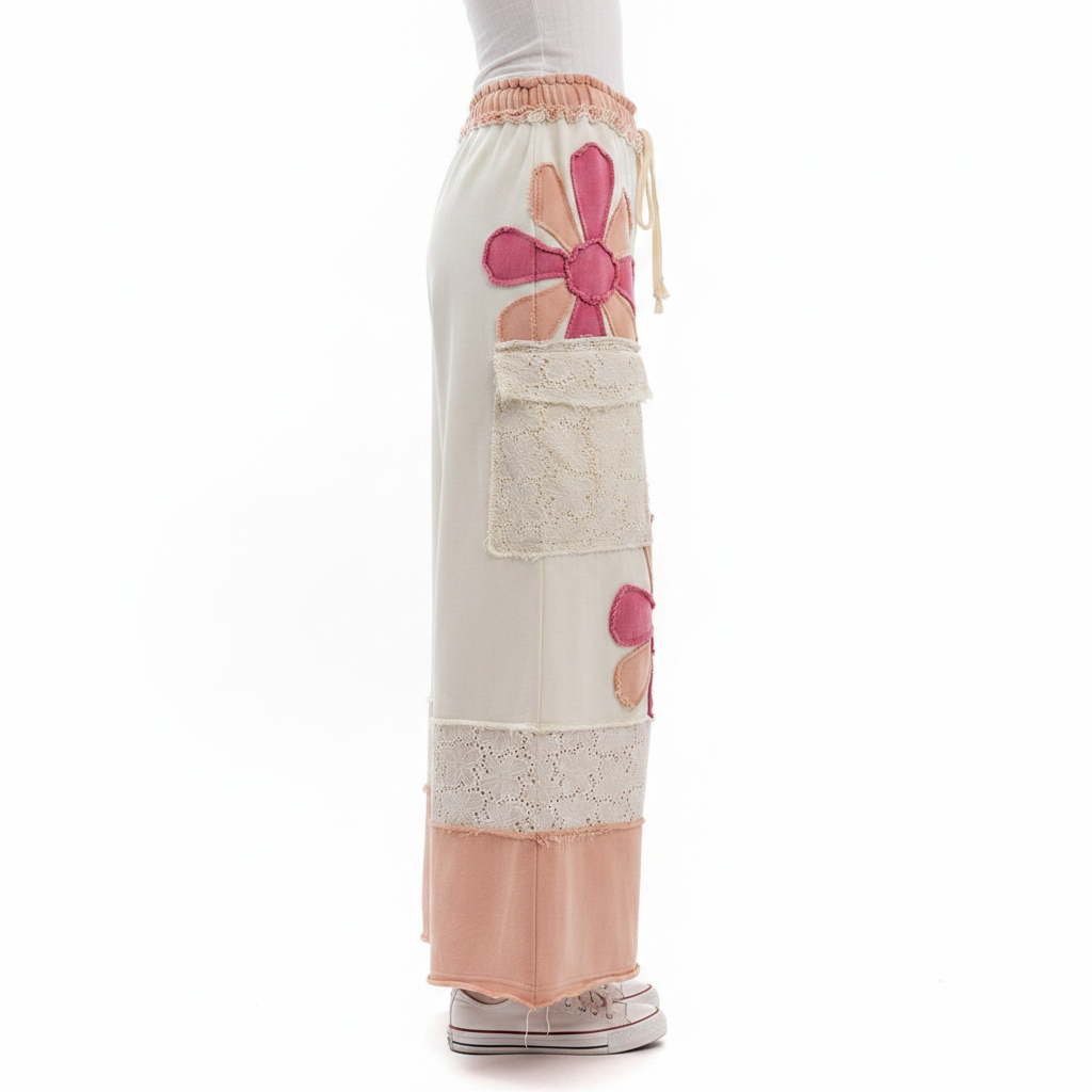 Women's cream floral patchwork pants side view, ghost mannequin, wide-leg silhouette, eyelet lace, peach hem