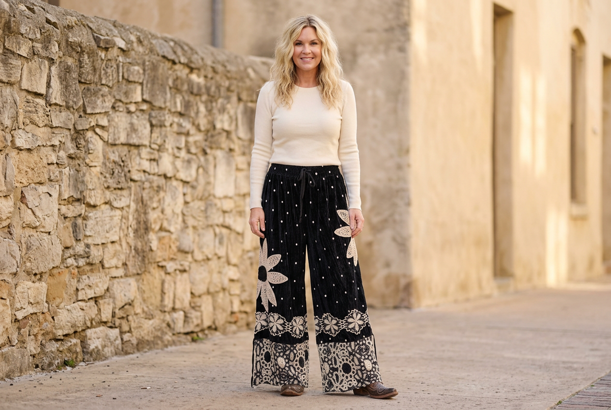 Full-length view of black velvet polka dot wide-leg pantaloons with crochet daisy appliqué and lace hems
