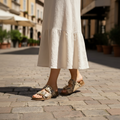 Close-up of snake print slide sandals with midi skirt on cobblestone street - European summer style