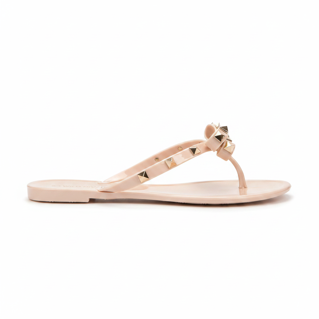 Nude blush jelly thong sandal with gold pyramid studs and bow, side profile view showing flat sole silhouette
