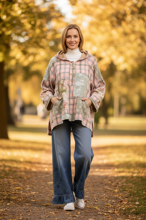 Woman wearing blush pink Bluevelvet oversized patchwork hoodie with floral and plaid patches styled with denim jeans lifestyle photo with bokeh background