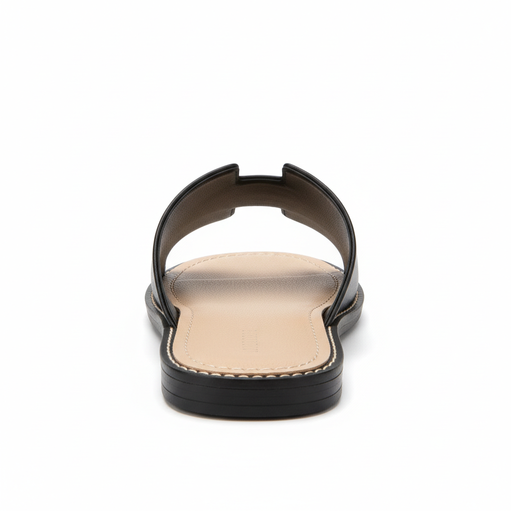 Black H-strap flat slide sandal, back heel view showing stitched footbed edge, white background