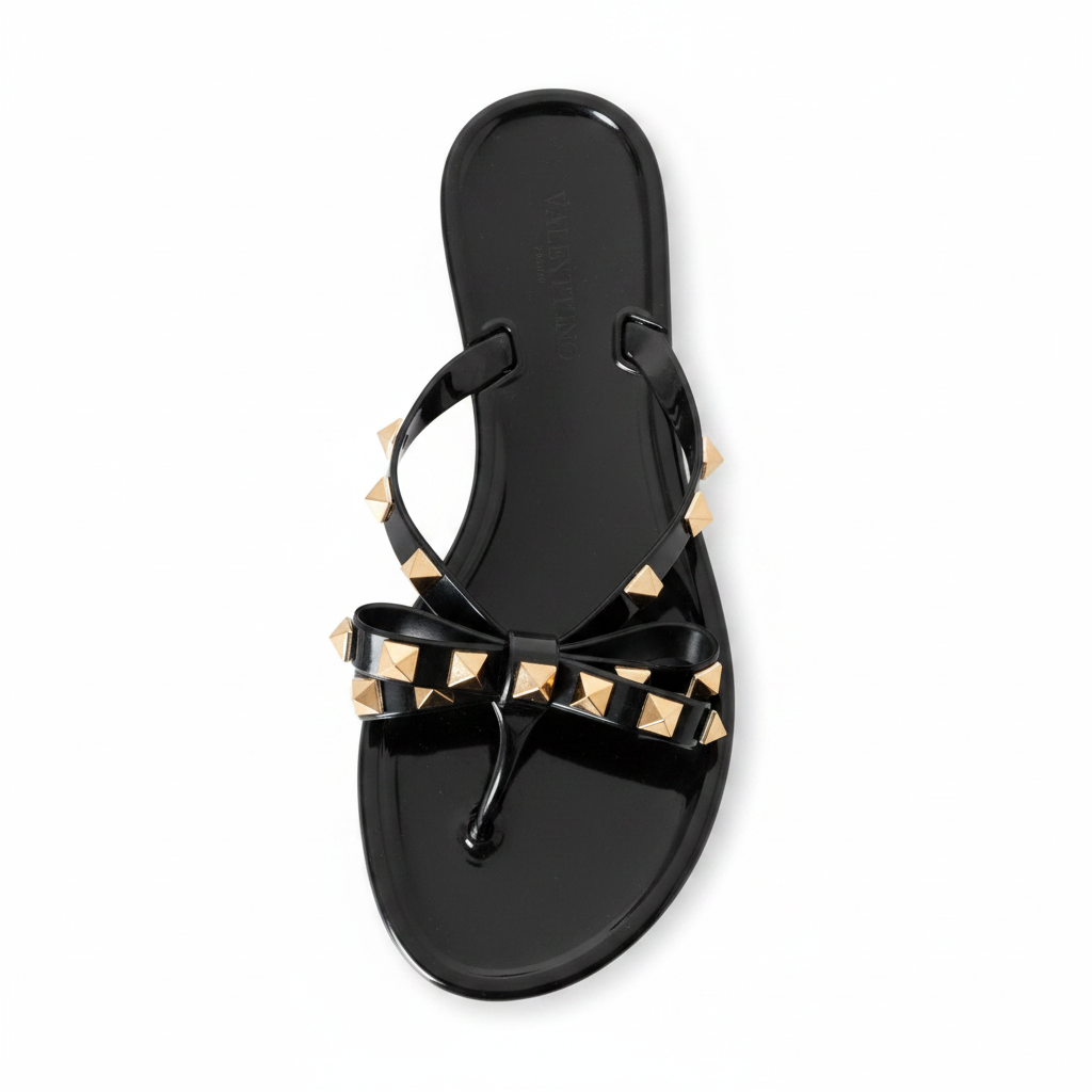 Black jelly thong sandal overhead top view showing gold studded bow detail and toe strap