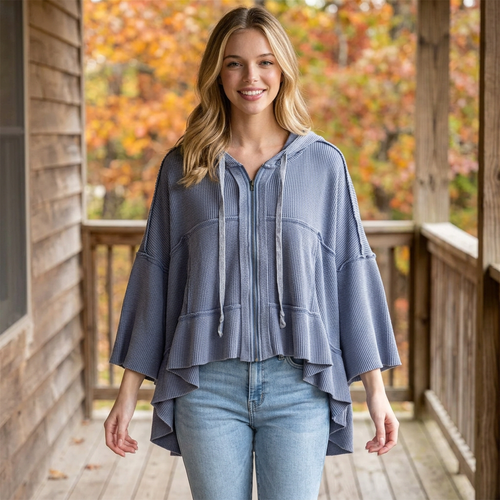 Light blue waffle zip hoodie with wide sleeves and a high-low hem, worn with jeans on a wooden porch