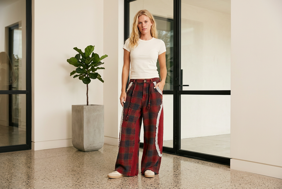 Wine plaid lace-trim pants with an ivory tee in a bright modern entrance with black-framed glass