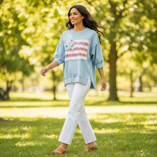 Women's light blue patchwork flag French terry pullover top in motion, drop shoulder, styled with white wide-leg denim