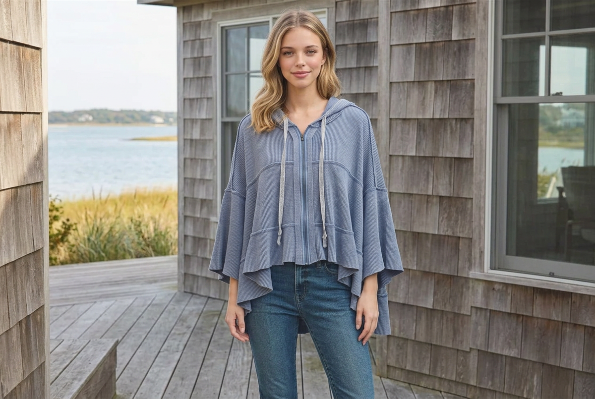 Woman wearing a light blue high-low waffle zip hoodie and jeans on a coastal cottage deck