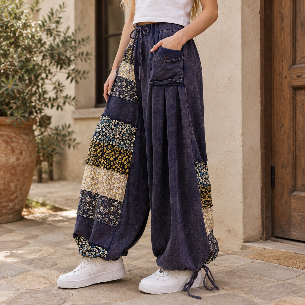 Sage + Fig navy wide-leg patchwork pants showing floral panels and adjustable hems in a courtyard