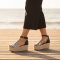 Women's snake print espadrille wedge sandal styled with black trousers on coastal boardwalk warm golden light