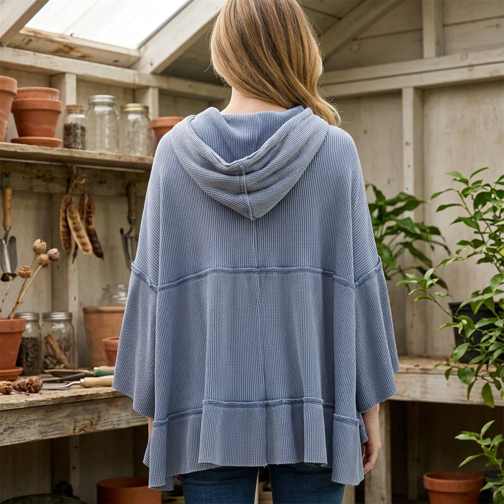 Back detail of a light blue waffle hoodie showing the draped hood, horizontal seams and gathered lower hem