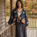 Black floral ruffle cardigan with balloon sleeves, worn with a cream top and charcoal skirt on a wooden porch.