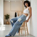 POL Clothing women's light blue barrel-leg patchwork jeans with heart appliqués, seated side view
