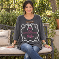 A Rare Bird Shop charcoal Girly graphic tee with sleeves past the elbow on a model seated on a garden bench