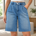 Close up of front pleats and silver button on Risen Jeans women's medium wash denim jorts