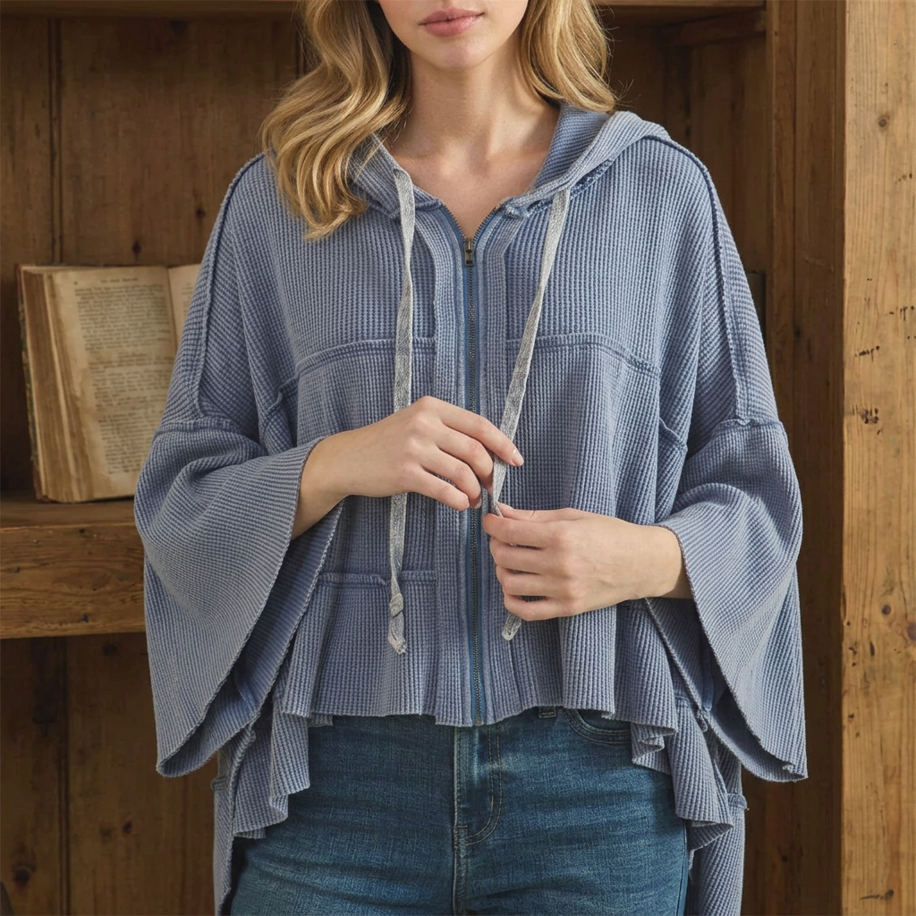 Front close-up of a light blue waffle hoodie showing drawstrings, zipper, exposed seams and gathered hem
