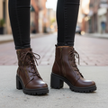 Woman standing in chocolate brown Soda combat ankle boots with skinny jeans on city sidewalk