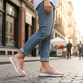 Woman wearing rose gold glitter sneakers with casual jeans walking on sunny city street