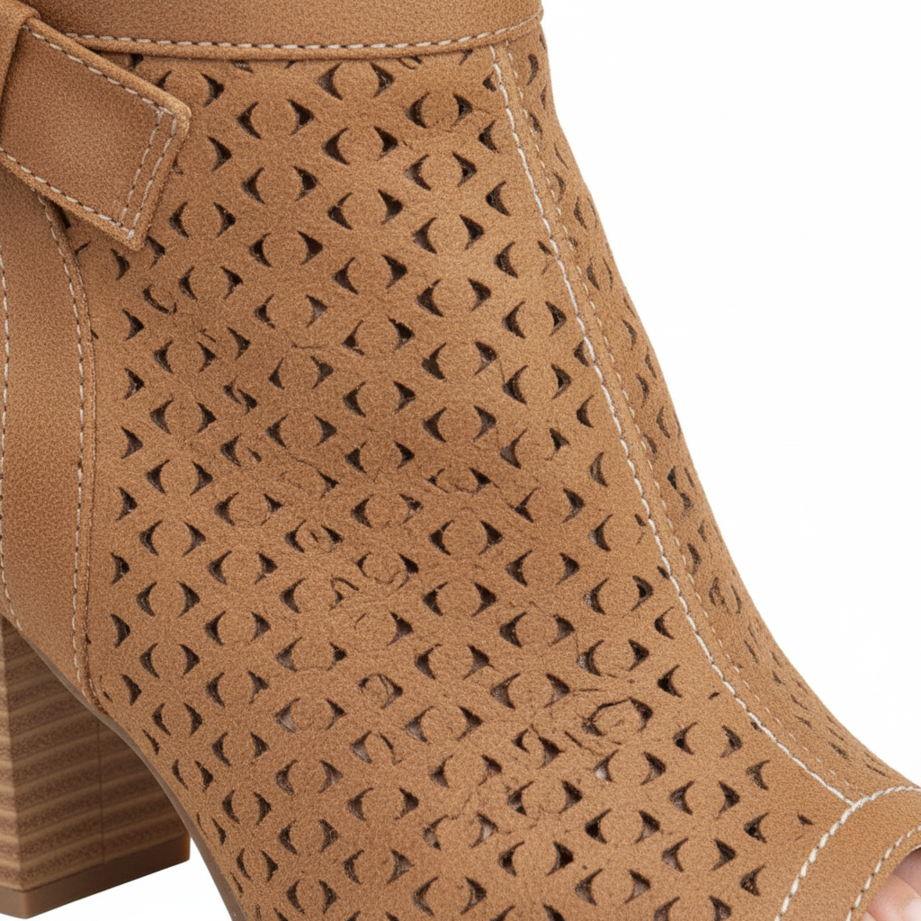 Close-up of laser-cut geometric perforated pattern and white contrast topstitching on tan faux suede bootie upper