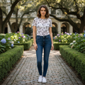 Woman standing in a garden with manicured hedges and flowers