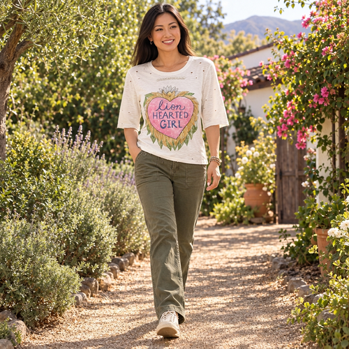 A Rare Bird Shop ivory Lion Hearted Girl tee with half sleeves past the elbow and olive trousers on a garden walk