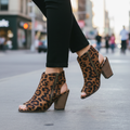 Woman walking in Forever Link Winster-2 leopard peep-toe cutout booties mid-stride, city street setting