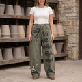 Olive graphic barrel jeans with a heart and white bird, styled with an ivory tee outside a pottery studio.