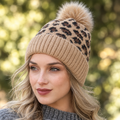 Close-up of Leto Collection camel leopard print ribbed knit beanie crown and tan faux fur pom pom