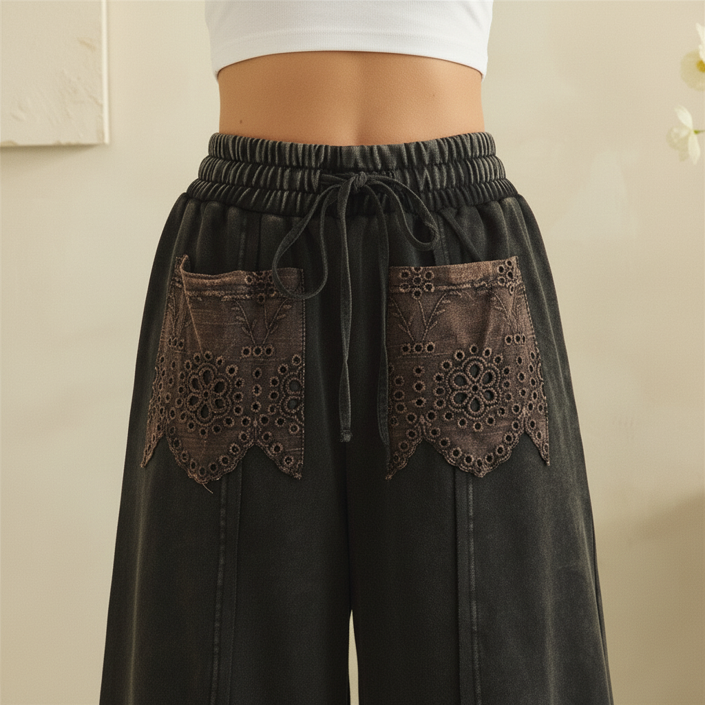 Detail of elastic drawstring waistband and eyelet lace patch pockets on black boho pants