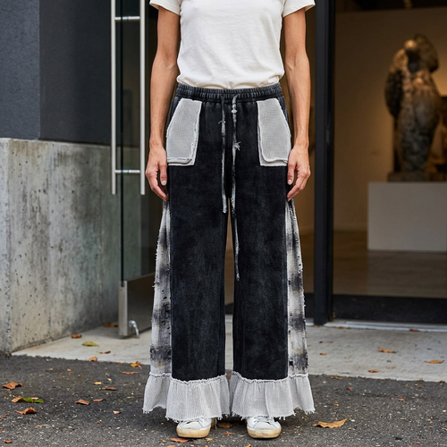 Black wide-leg pants with pale patch pockets, plaid side panels and ruffle hems outside an art gallery.