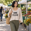 Miracle women's beige Wine Please sweater with black lettering at a farmers market
