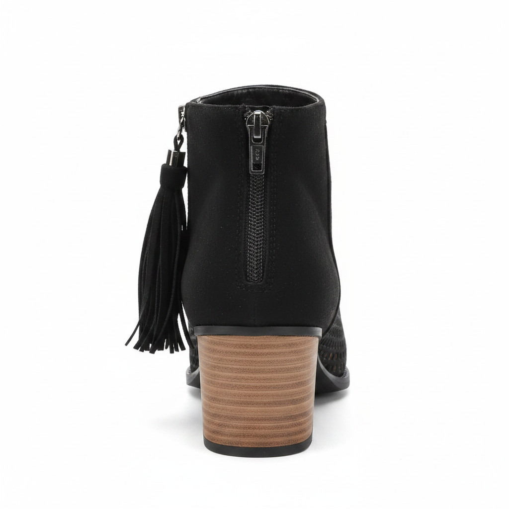 Black perforated peep-toe bootie back view showing fringe tassel zipper pull and stacked block heel on white background