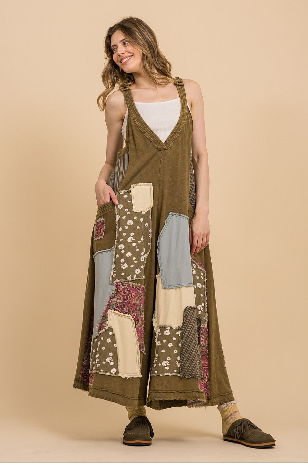 Woman wearing a long, patchwork dress against a beige background