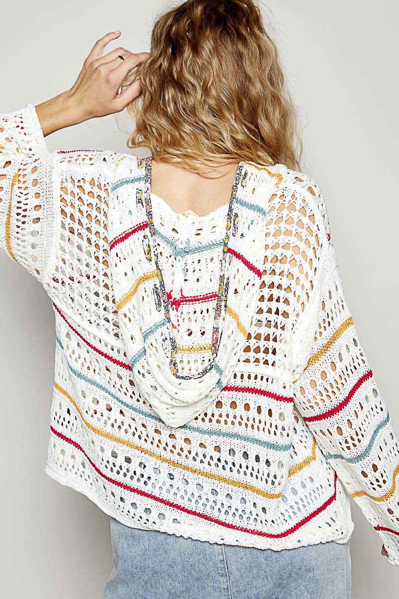 Woman wearing a colorful striped crochet top against a plain background