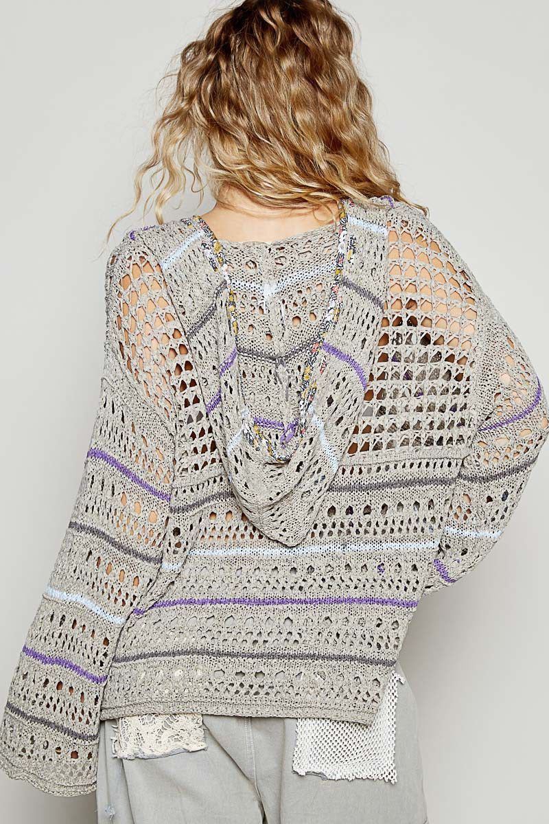 Person wearing a crocheted sweater with intricate patterns on a plain background