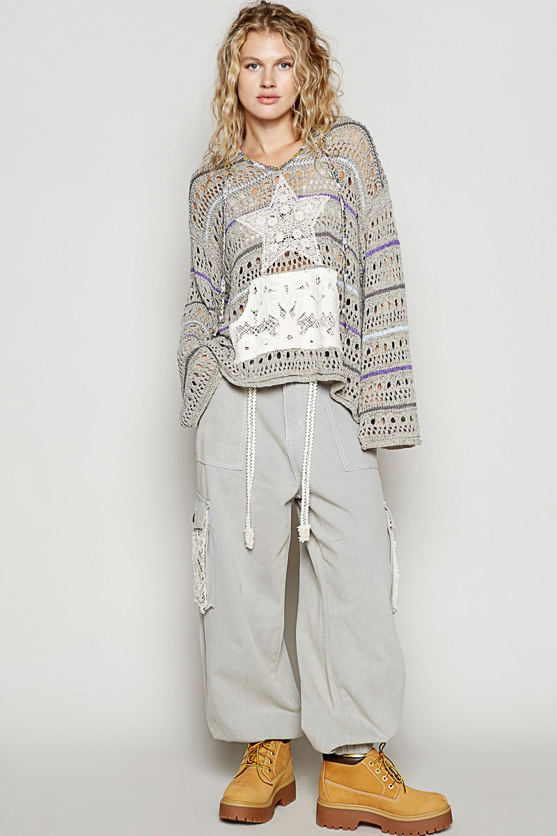 Person wearing a patterned sweater, light gray cargo pants, and tan boots on a plain background