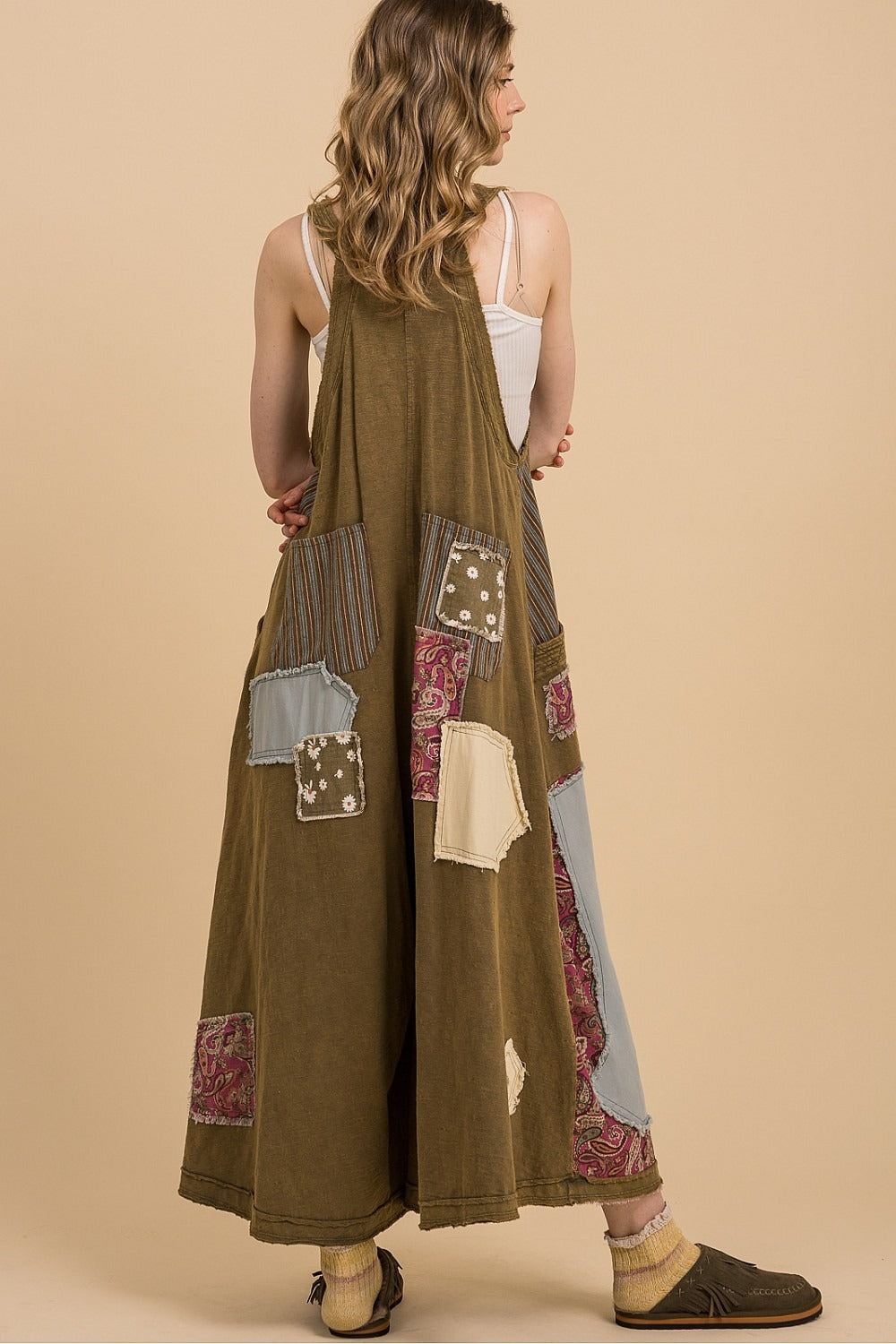 Woman wearing a long, patterned dress against a beige background