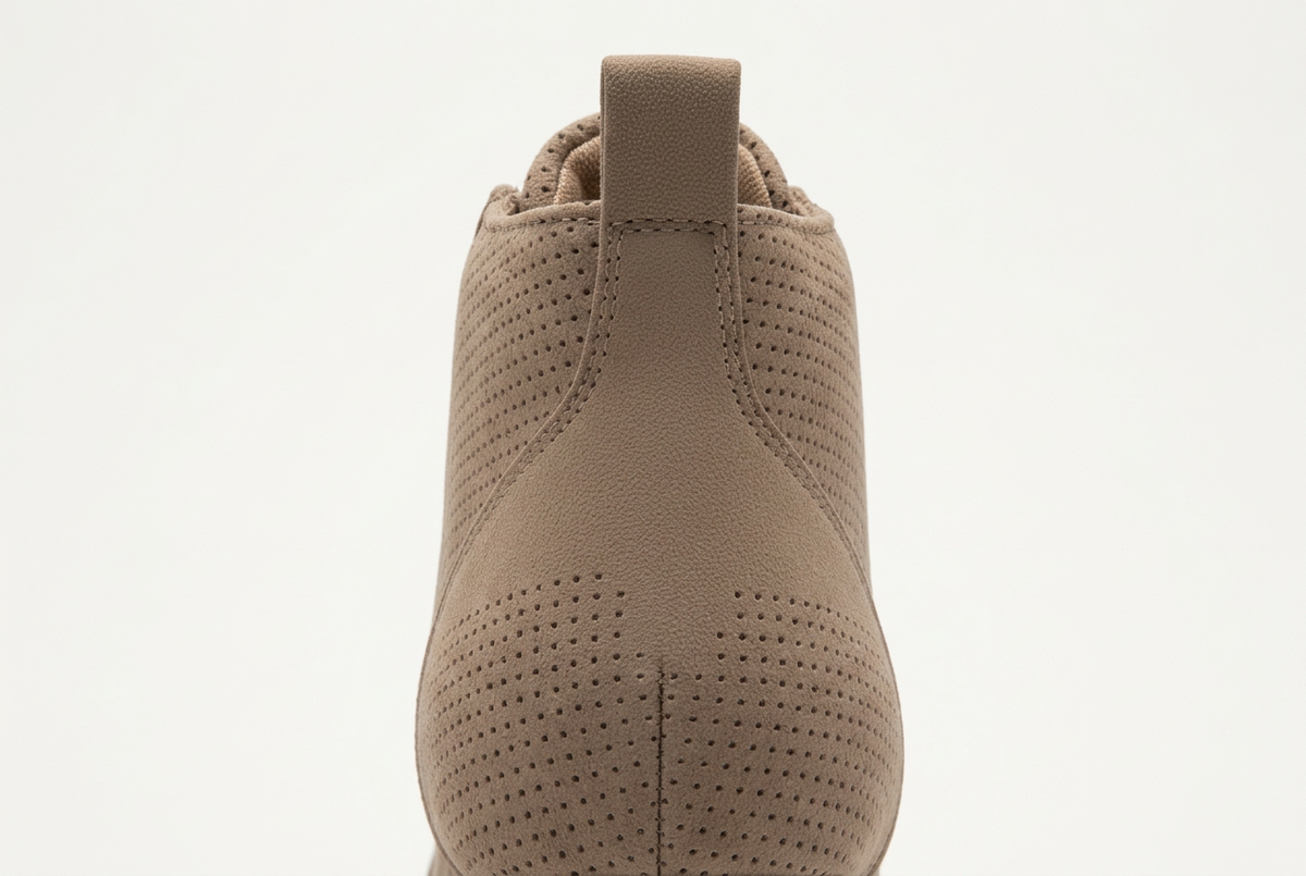 Close-up rear view of a taupe brown perforated suede ankle boot against a white background.