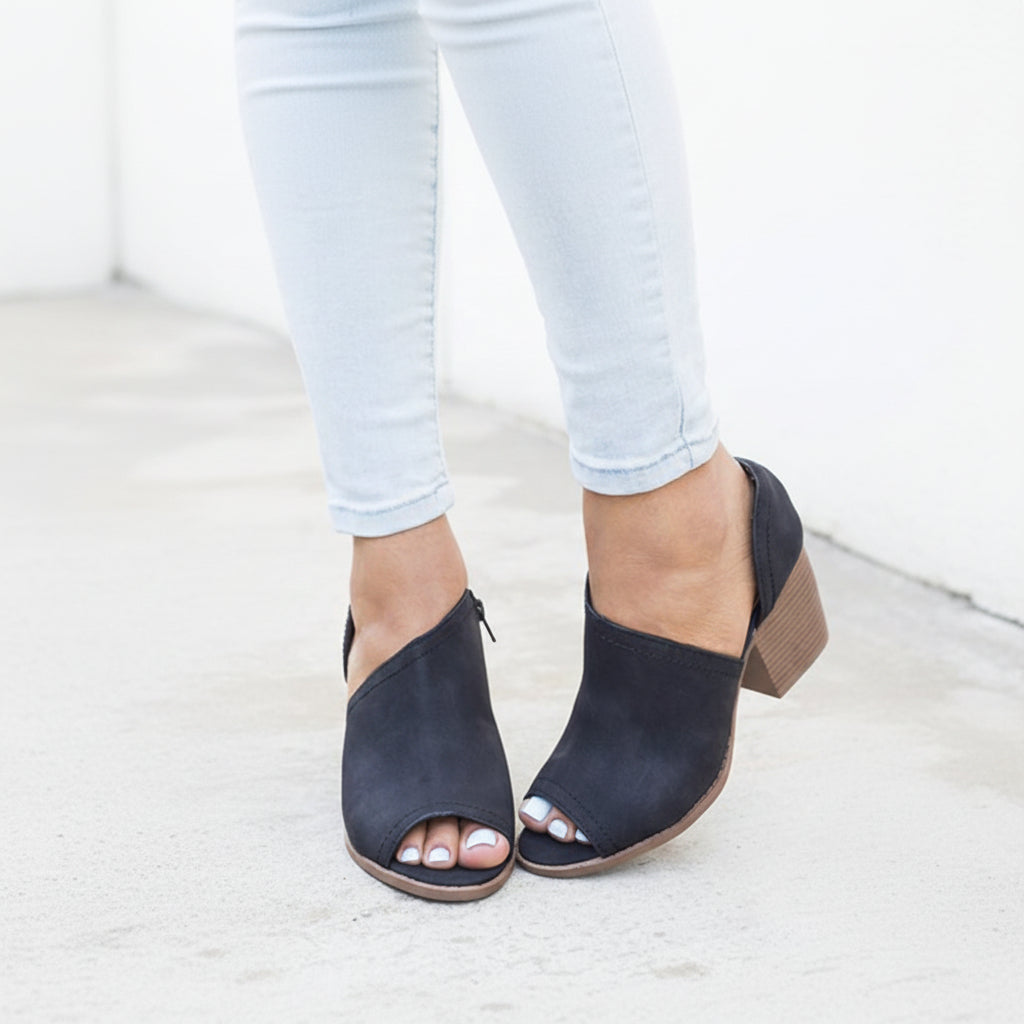 Qupid Black peep-toe cutout ankle bootie on model with cuffed light wash jeans, outer V cutout and block heel visible
