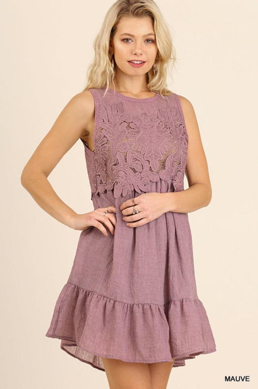 A girl front facing modeling a mauve color, sleeveless, ruffled dress.